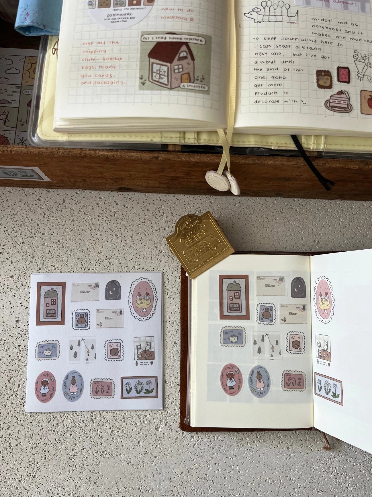 Open book with illustrations and a sheet of kawaii bunny and bear stickers on a textured surface