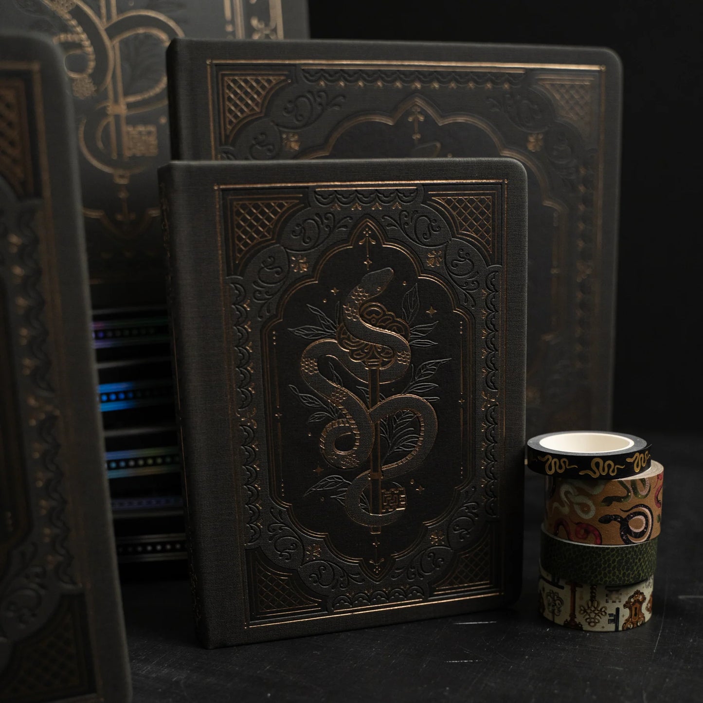 Decorative black books with intricate designs on a dark background