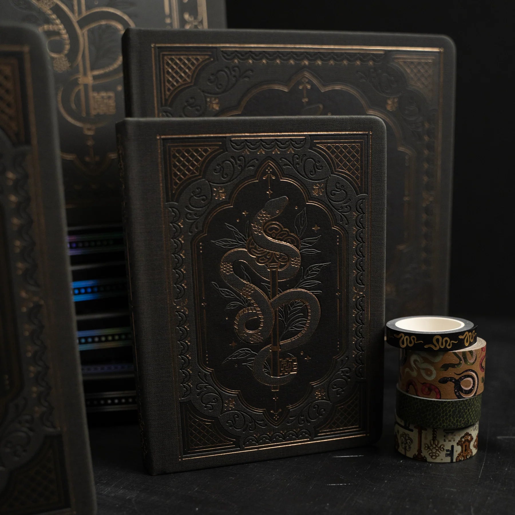 Decorative black books with intricate designs on a dark background