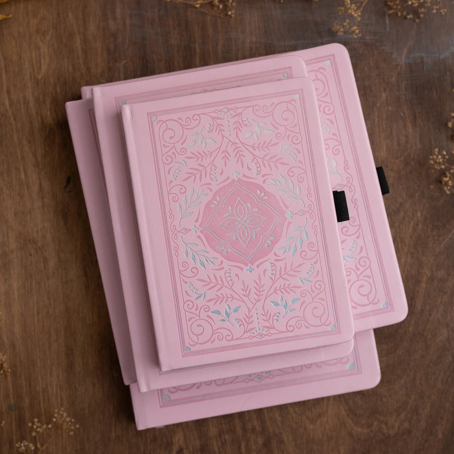 Archer and Olive Storybook in Pink  Notebook with silver and pink debossed  pattern. A soft delicate pattern that spans the full width of the cover. This shows a stack of the Pink Storybook notebooks in a variety of sizes.