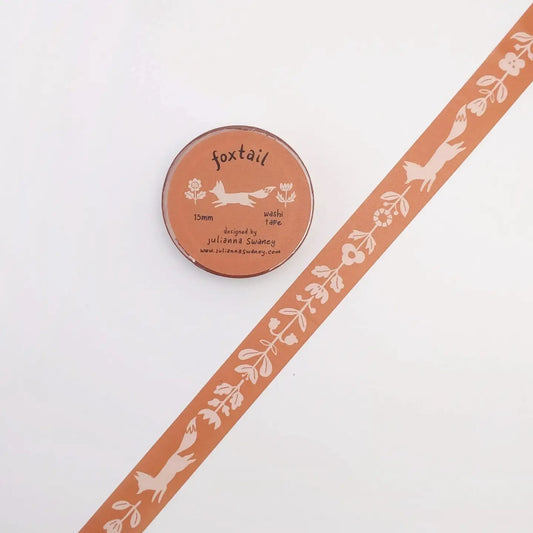 A roll of washi tape pink with white folk decorations of flowers and foxes.