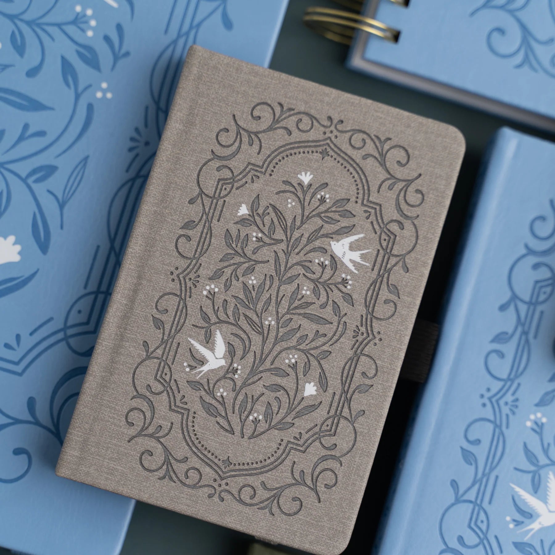 Archer and Olive Decorative notebook with floral and bird pattern on a blue textured background