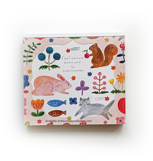 Aiko Fukawa memo pad with animal and floral illustrations in vibrant colors on a white and pink background. A squirrel, a bunny, a cat, and two fish. Includes a watermark for The Cozy Journal which captured and edited the product photo.